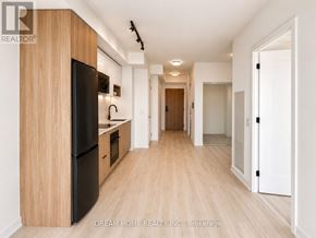 Toronto (Regent Park) condo for rent - A modern kitchen with wooden cabinets and a black fridge.