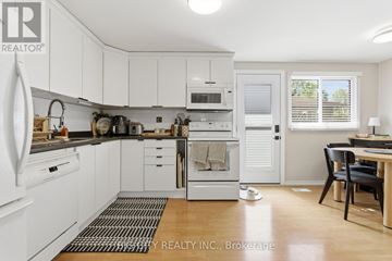 Oshawa (Donevan) apartment for rent - A white kitchen with a black chair and a black dog.