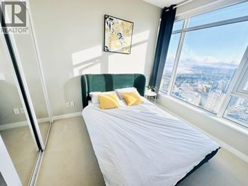 Burnaby apartment for rent - A bedroom with a large bed and a view of the city.