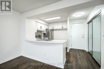 Mississauga (Hurontario) condo for rent - A kitchen area with white cabinets and a wooden floor.