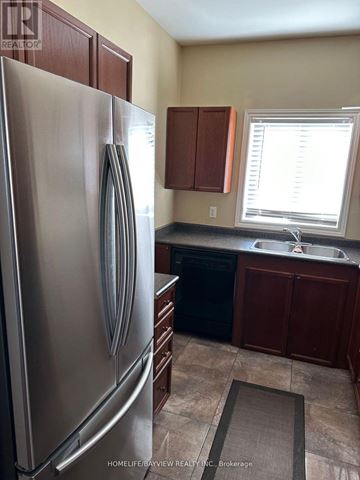 Barrie (Painswick South) apartment for rent - A kitchen with a stainless steel refrigerator and wooden cabinets.