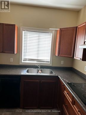 Barrie (Painswick South) apartment for rent - A kitchen with brown cabinets and a black dishwasher.