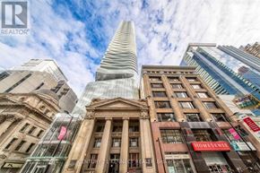 Toronto (Church-Yonge Corridor) condo for rent - A tall building with a pointed top stands in front of a row of older buildings.