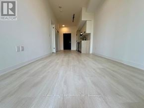 Burlington (Alton) condo for rent - A spacious room with wooden flooring and white walls.