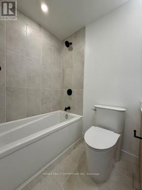 Burlington (Alton) condo for rent - A white bathroom with a toilet, tub, and tiled walls.