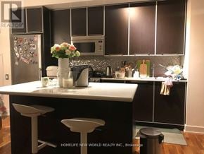 Toronto (Willowdale East) condo for rent - A kitchen with black cabinets and a white countertop.