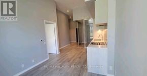 Vaughan (Vaughan Corporate Centre) condo for rent - A brokerage sign is displayed on a wall in a spacious room with a kitchen area.