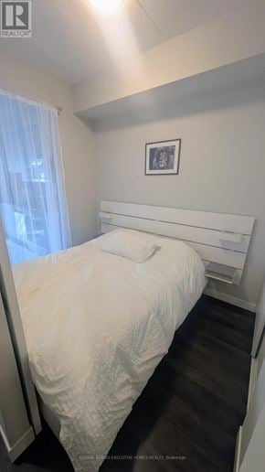 Hamilton (Central) condo for rent - A bedroom with a bed, a picture on the wall, and a window with curtains.