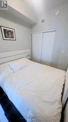 Hamilton (Central) condo for rent - A bed with white sheets and a white pillow is in a room with a picture on the wall.