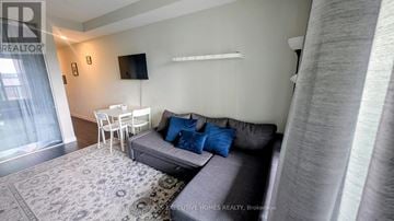 Hamilton (Central) condo for rent - A living room with a grey couch and a white table.