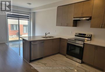 North Dumfries townhouse for rent - A kitchen with a stainless steel dishwasher and oven, and wooden cabinets.