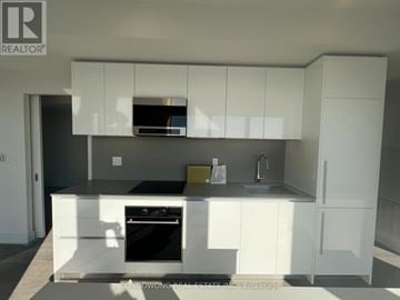 Toronto (Annex) condo for rent - A modern kitchen with white cabinets and a black countertop.