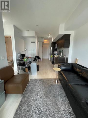 Toronto (Mimico) condo for rent - A living room with a black couch and a brown leather chair.