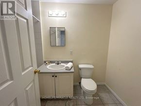 Toronto (Kennedy Park) townhouse for rent - A bathroom with a toilet, sink, and mirror.