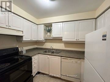 Toronto (Kennedy Park) townhouse for rent - A kitchen with white cabinets and a black stove top oven.