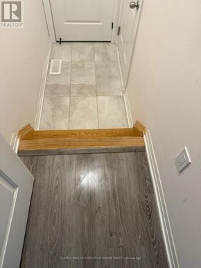 Clarington (Bowmanville) townhouse for rent - A hallway with a wooden floor leading to a white door.