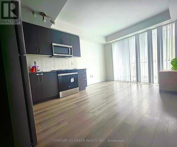 Brampton (Brampton West) condo for rent - A kitchen with black cabinets and a wooden floor.
