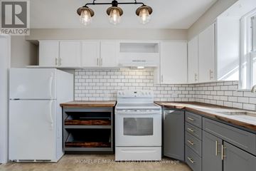Brampton (Downtown Brampton) apartment for rent - A white refrigerator and stove in a kitchen with white cabinets and a white backsplash.
