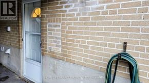 Brampton (Northwood Park) apartment for rent - A green hose is hanging on a brick wall next to a white door.