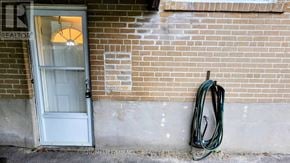 Brampton (Northwood Park) apartment for rent - A green hose is hanging on a brick wall next to a door.