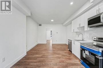 Niagara Falls (Arad/Fallsview) townhouse for rent - A kitchen with white cabinets and a wooden floor.
