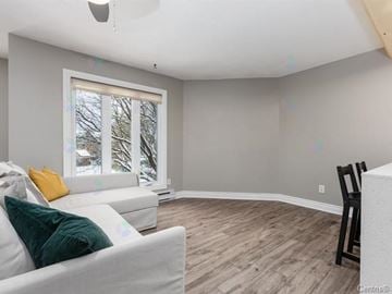 Gatineau (Hull) condo for rent - A living room with a white couch and a wooden floor.