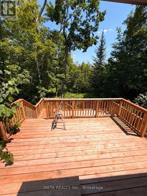 Trent Lakes apartment for rent - A wooden deck with a chair and a table in the middle of it.