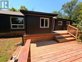 Trent Lakes apartment for rent - A wooden deck with a house in the background.
