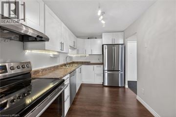 Brantford condo for rent - A kitchen with white cabinets and a stainless steel refrigerator.
