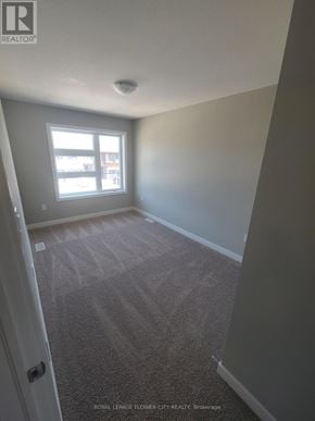Kitchener townhouse for rent - A carpeted room with a door and a window.