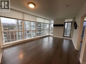 Coquitlam apartment for rent - A spacious room with wooden floors and large windows overlooking a cityscape.