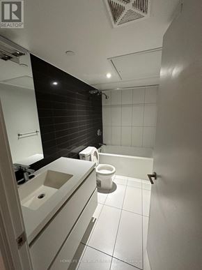 Toronto (Waterfront Communities) condo for rent - A bathroom with a toilet, sink, and mirror.