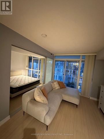 Toronto (Waterfront Communities) condo for rent - A bedroom with a bed and a couch with a window in the background.
