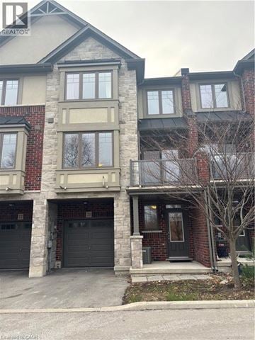 Ancaster townhouse for rent - A two-story brick house with a garage and a tree in front.