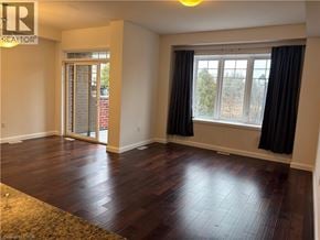 Ancaster townhouse for rent - A room with wooden flooring and a window with black curtains.