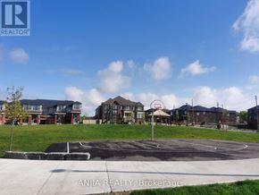 Pickering townhouse for rent - A basketball court is in the middle of a grassy area in front of a row of houses.