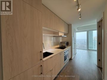 Toronto (Mount Pleasant East) condo for rent - A kitchen with wooden cabinets and a stainless steel stove top oven.