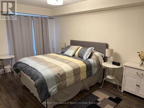 Collingwood townhouse for rent - A bedroom with a large bed and a nightstand with a lamp.