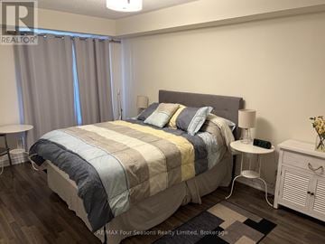 Collingwood townhouse for rent - A bedroom with a large bed and a nightstand with a lamp.