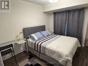 Collingwood townhouse for rent - A bedroom with a bed, nightstand, chair, and window with curtains.