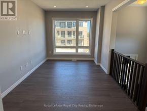 Guelph (Kortright East) townhouse for rent - A room with a large window and wooden flooring.