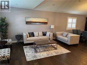 Niagara Falls apartment for rent - A living room with a white sofa, a white armchair, a coffee table, and a painting on the wall.