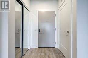 Toronto (Dovercourt-Wallace Emerson-Junction) condo for rent - A hallway with white walls and a wooden floor leading to a white door.