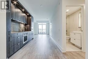 Toronto (Dovercourt-Wallace Emerson-Junction) condo for rent - A spacious kitchen with dark wood cabinets and a white countertop.