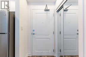 Hamilton (Waterdown) condo for rent - A white door with a blue sign on it is in a hallway.