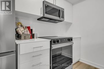 Centre Wellington (Fergus) townhouse for rent - A modern kitchen with a stainless steel refrigerator, white cabinets, and a microwave mounted above the stove.