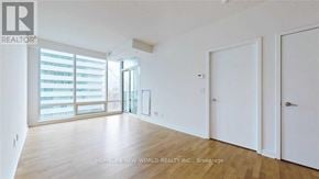 Toronto (Waterfront Communities) condo for rent - A spacious room with wooden flooring and white walls, featuring a sliding glass door leading to a balcony.