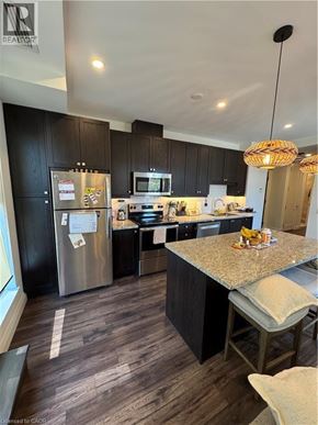 Hamilton condo for rent - A kitchen with a granite counter top and a refrigerator with magnets on it.