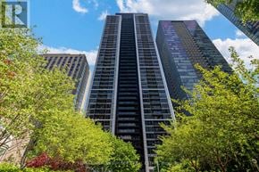 Toronto (Church-Yonge Corridor) condo for rent - A tall building with a glass facade stands in front of a sky filled with clouds.