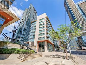 Toronto (Waterfront Communities) condo for rent - A modern building with a glass facade is surrounded by other tall buildings.